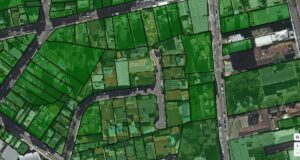 Uma visão detalhada de uma cidade com lotes demarcados em diferentes tonalidades de verde. Esse é um exemplo do uso de SaaS para geoprocessamento aplicado à gestão municipal, facilitando a atualização cadastral, fiscalização e tomada de decisões estratégicas sobre o território. Essas soluções na nuvem otimizam o trabalho de prefeituras e empresas, permitindo análise espacial avançada e integração eficiente dos dados urbanos.