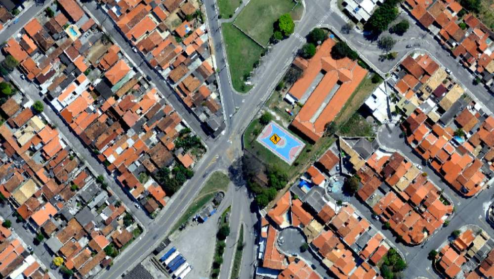 Aerolevantamento é o que falta para sua prefeitura enxergar onde está perdendo arrecadação A imagem mostra um exemplo claro dos resultados obtidos por meio de aerolevantamento: uma captura aérea de alta resolução que permite visualizar com nitidez a malha urbana, incluindo ruas, quadras, construções e equipamentos públicos, como a quadra esportiva no centro da imagem.