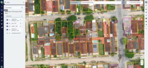 Interface de sistema de Cadastro Técnico Multifinalitário mostrando mapa ortofoto com lotes urbanos delimitados por polígonos coloridos