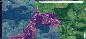 Área urbana destacada em roxo sobre imagem aérea, indicando zoneamento usado para análise territorial e arrecadação municipal.