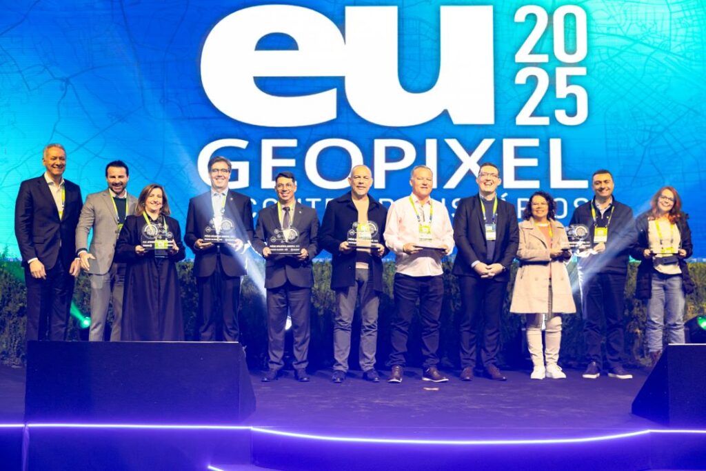 Equipe Geopixel recebendo prêmio de reconhecimento como autoridade em geointeligência municipal no evento eu 2025, com representantes no palco segurando troféus que celebram a liderança da empresa no fornecimento de soluções tecnológicas para gestão pública.
